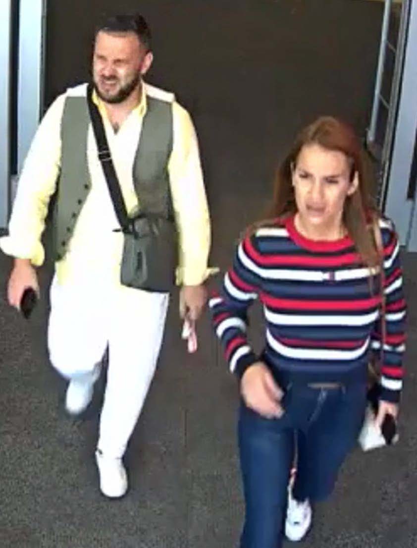 Camera footage photo of initial male suspect and female suspect wearing jeans, white tennis shoes and a red, blue and white striped long sleeve shirt.